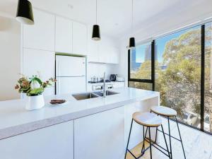 uma cozinha branca com um lavatório e 2 bancos em Bright 3 level townhouse em Melbourne