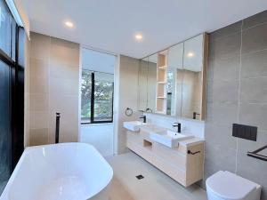 uma casa de banho com uma banheira, 2 lavatórios e um WC. em Grandeur Innercity Townhouse em Melbourne