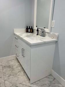 a white bathroom with a sink and a mirror at River View House Basement in Kamloops