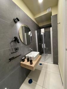 ein Bad mit einem Waschbecken, einem Spiegel und einer Dusche in der Unterkunft Casa Corallium in Torre del Greco