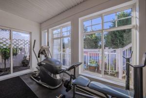 een kamer met een fitnessruimte met een loopband en ramen bij Cherry Lane Suite - studio ground suite w garden in Nanaimo