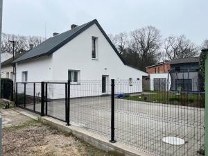 une clôture devant une maison blanche dans l'établissement Celý dům + zahrada, à Pardubice