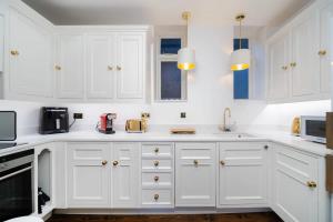 uma cozinha branca com armários e electrodomésticos brancos em Stylish 2-Bed Flat in London em Londres