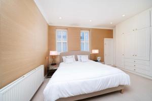 um quarto com uma grande cama branca e 2 candeeiros em Stylish 2-Bed Flat in London em Londres
