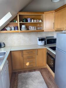 eine Küche mit Holzschränken und einem weißen Kühlschrank in der Unterkunft Lahinch Central 3-Bed Retreat in Lahinch