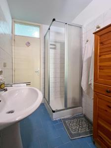 La salle de bains blanche est pourvue d'une douche et d'un lavabo. dans l'établissement Elios Home Bellavista - Taormina Letojanni, à Letojanni