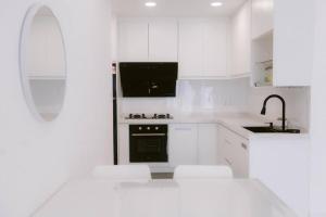 カンパング・デンキルにあるLA CASABAYU HOMESTAYの白いキッチン(白い家電製品、白いキャビネット付)