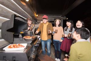 Un groupe de personnes autour d'une cuisine préparant des repas dans l'établissement Yufuin Log House no Yado Tom Sawyer, à Yufu