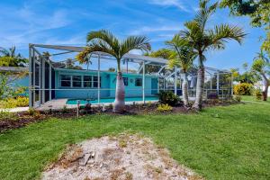 ein blaues Haus mit Palmen im Hof in der Unterkunft Gecko Getaway in Fort Myers