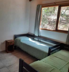 2 camas en una habitación con ventana en Las Casitas del Pozo en Villa General Belgrano