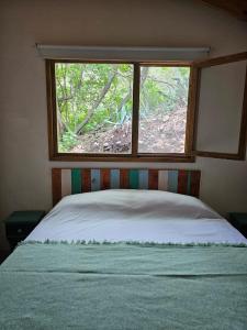 a bedroom with a bed in front of a window at Las Casitas del Pozo in Villa General Belgrano