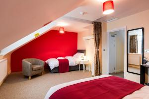 a bedroom with a red wall with a bed and a chair at Train Station Hotel in Norwich