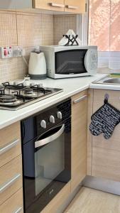 a kitchen with a stove and a microwave at PMP Adamia Apartments in Peyia