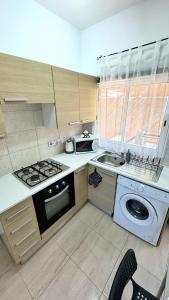 a kitchen with a stove and a washer and sink at PMP Adamia Apartments in Peyia