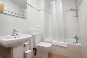 a white bathroom with a toilet and a sink at Casa Rosi 1 in Puerto del Rosario +16 photos