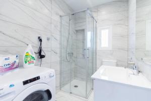 a white bathroom with a shower and a washing machine at BRAND NEW PENTHOUSE TERRACE BBQ WIFI MODERN MALAGA in Málaga