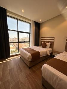 um quarto de hotel com duas camas e uma grande janela em نمو الديار em Al ‘Azīzīyah
