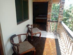 un porche con 2 sillas y una cama en una habitación en Maliga inn, en Gampola