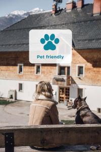 a woman sitting next to a dog in front of a pet friendly sign at Apartmaji Triglav in Bohinj
