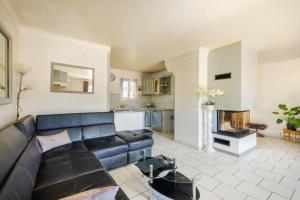 ein Wohnzimmer mit einem schwarzen Sofa und einem Kamin in der Unterkunft Villa 6 pers avec piscine in Le Tignet
