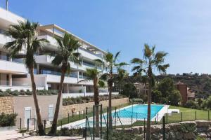 ein großes Apartmenthaus mit einem Pool und Palmen in der Unterkunft LUXURY PENTHOUSE MARBELLA WIFI POOLS NETFLIX GOLF in Benahavís