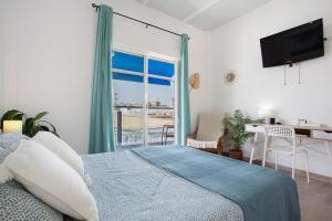 Un dormitorio con una cama y un escritorio y una ventana. en Alojamiento El Ocaso, en Puerto del Rosario