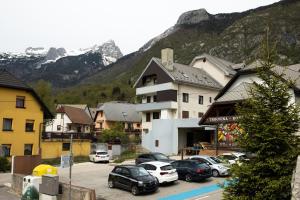 a town with cars parked in a parking lot with mountains at Svarun apartment in Bovec