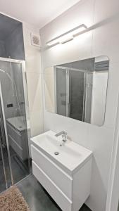 La salle de bains blanche est pourvue d'un lavabo et d'un miroir. dans l'établissement Apartament Górski z widokiem na góry w Bieszczadach - 3 sypialnie 80m2, à Ustrzyki Dolne