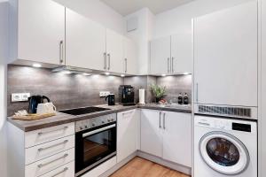 Una cocina con gabinetes blancos y lavadora y secadora. en Km Style Apartments 4, en Freiburg im Breisgau