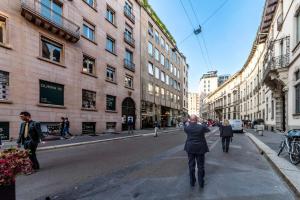 Una persona che cammina per una strada in una città di Dream Suites Milano San Babila a Milano