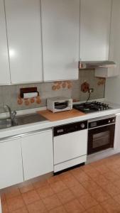 a kitchen with white cabinets and a stove top oven at Via Verdi Apartment in Imola