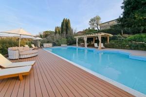 a swimming pool with chairs and umbrellas on a wooden deck at Le Valli Tuscany in Pomarance