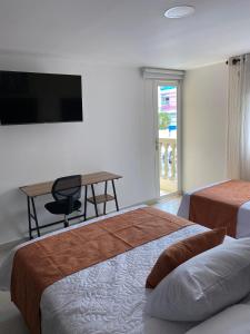 una camera con 2 letti, una scrivania e una TV di Sachar Lodging Apartahotel a Bucaramanga