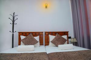 a bedroom with two beds with brown and white pillows at Kandy Tower Inn in Kandy