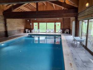 a swimming pool in a wooden house with chairs around it at Bois de Champelle -7- Magnifique chalet 8 pers in Morillon