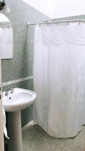 La salle de bains est pourvue d'un rideau de douche blanc et d'un lavabo. dans l'établissement Dpto Céntrico en Catamarca Capital, à San Fernando del Valle de Catamarca