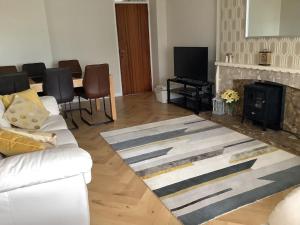 a living room with a white couch and a fireplace at Carrick House, Mid-Ulster in Knockcloghrim