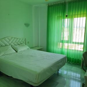 a bedroom with a bed with green curtains and a window at LAS MIMOSAS PARADISE in La Cala de Mijas