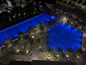 una vista aérea de una piscina con palmeras y luces en Reverie Sky Home An Bang Beach, en Dien Ban