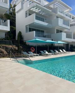 basen z krzesłami i parasolami obok budynku w obiekcie Palo Alto Apartment Indoor Pool Gym View Wifi Parking w Marbelli