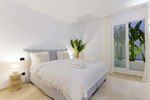 a white bedroom with a white bed and a window at DUPLEX PENTHOUSE ROOFTOP TERRACE SEA VIEWS WiFi in Benahavís