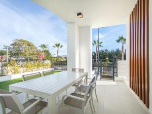Une table à manger et des chaises blanches sont disponibles sur la terrasse. dans l'établissement Duplex 3 Bedrooms Wifi Pools Jacuzzi, à Estepona