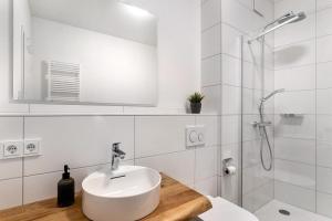 ein weißes Bad mit einem Waschbecken und einer Dusche in der Unterkunft Km Style Apartments 8 in Freiburg im Breisgau
