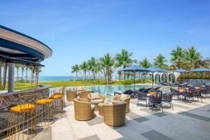 un patio del complejo con mesas y sillas y una piscina en Reverie Sky Home An Bang Beach, en Dien Ban