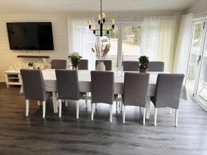 a dining room table with chairs and a television at Large villa with SPA and lake view outside Hultsfred in Vena