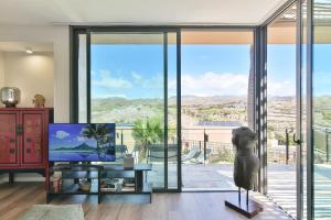 a living room with a tv and a large glass window at Los Lagos 37 by VillaGranCanaria in Las Palmas de Gran Canaria