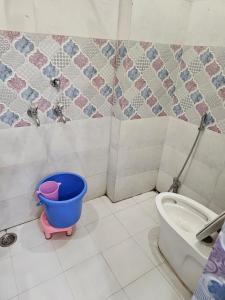 a bathroom with a bucket next to a toilet at Goroomgo Gautam Garden Varanasi in Varanasi