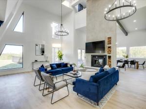 - un salon avec des canapés bleus et une cheminée dans l'établissement Modern Home - 1 Acre Lot w Pool Patios Jacuzzi, à Denton