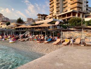 a group of people sitting on a beach with umbrellas at SHEMO Apartments in Sarandë