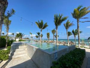 una piscina junto a la playa con palmeras en Big 5BR Home for an epic time in Riviera Maya, en Akumal